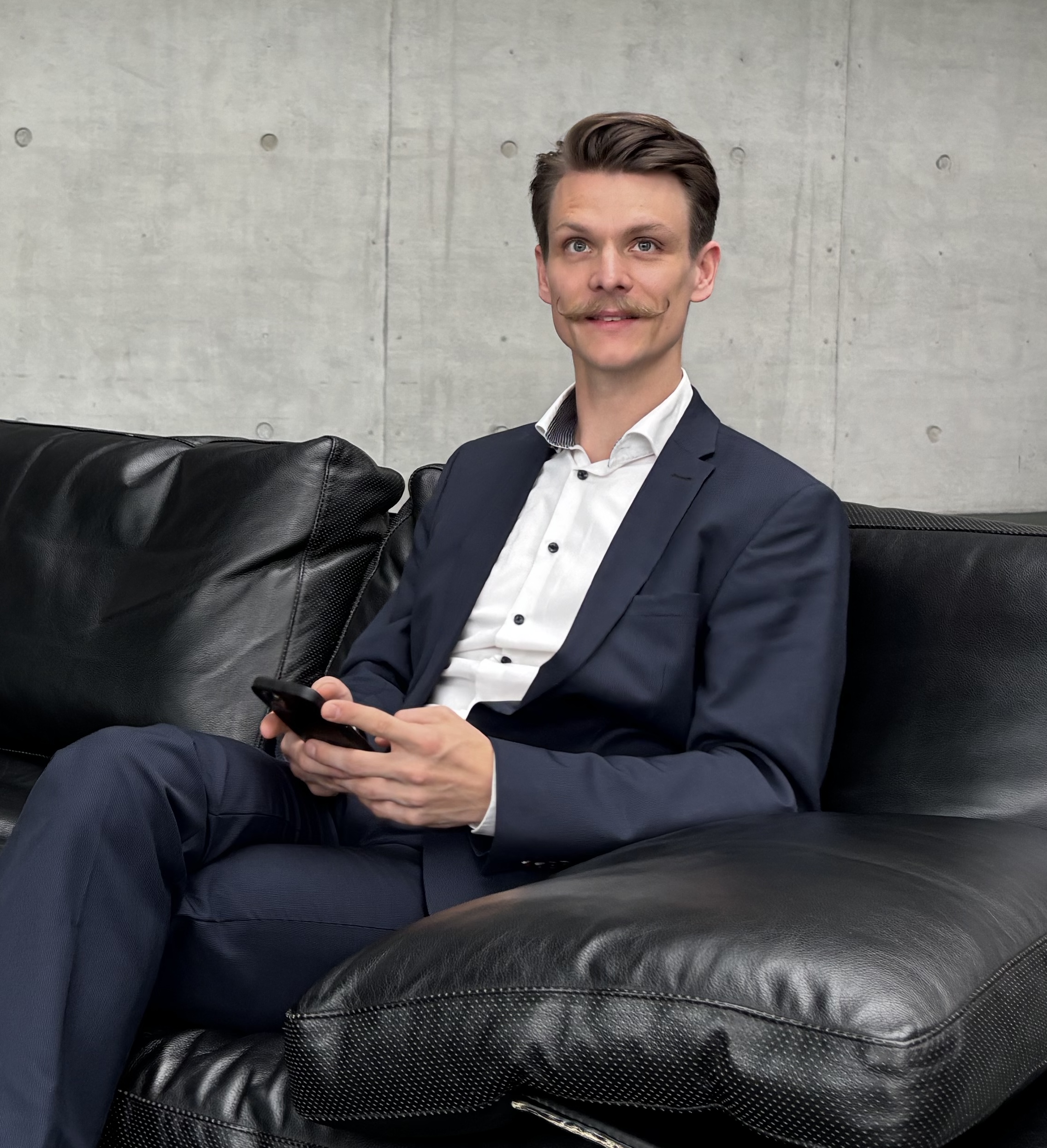 Marc Strobel, Berater für unternehmerisches Sparring sitzt am Handy auf dem Sofa.